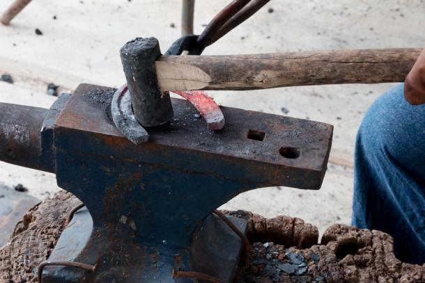 A farrier making horseshoes from iron in the old way. (sakdinon / Adobe Stock)