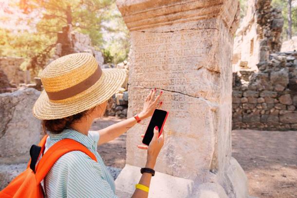 A female Western tourist translating ancient Greek text looking for knowledge or looking for misogyny? (EdNurg / Adobe Stock)