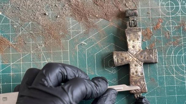 A conservator applies delicate conservation work to the intact, permanently sealed bronze reliquary cross found at Lystra.