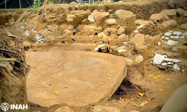 A large carved monolithic sculpture slab in the excavation trench, Coatepec, Veracruz.