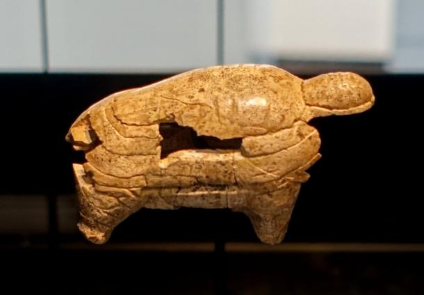 A small mammoth figure carved from mammoth ivory, shown on a museum stand