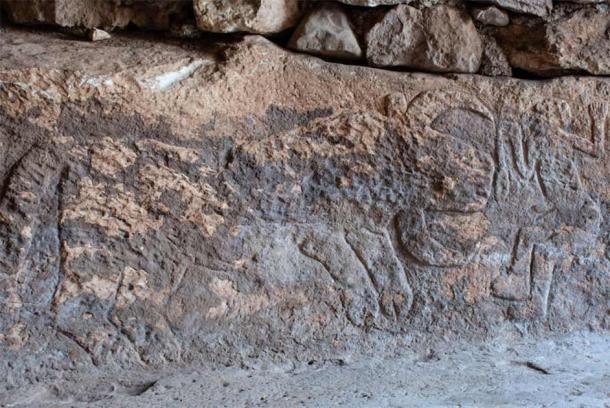 Un hombre con seis dedos y una serpiente en una mano frente a un toro con grandes cuernos, en el lado izquierdo del relieve de piedra. (Arkeolojihaber)