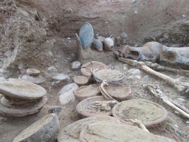 In the foreground various bowls and cups with animal remains under study, and in the background a mirror, three skyphoi,an alabaster and two painted oenochoes (jugs) (Image: Roland Haurillon, Inrap)