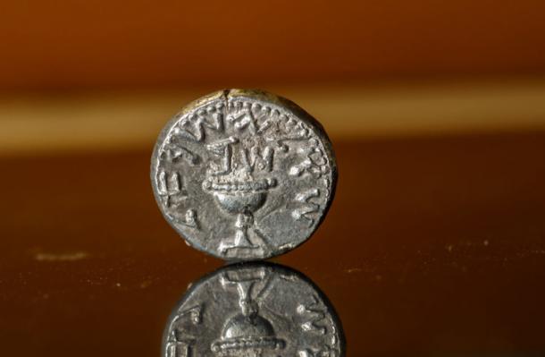 El anverso y el lado mejor conservado de la moneda del Segundo Templo, grabado con una taza y la leyenda 