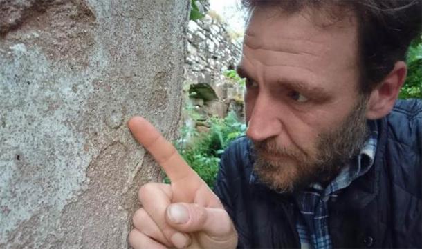 Ash inspectant une marque de sorcière au cimetière de Balnacoil datant du milieu du 18e siècle. (Ashley Cowie)