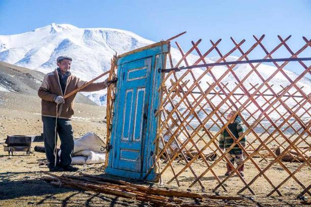With practice, a family could pack or unpack their yurt home in about an hour. This Kazakh man is assembling a ger for guests while his child plays inside. (NuclearApples / CC BY SA 4.0)