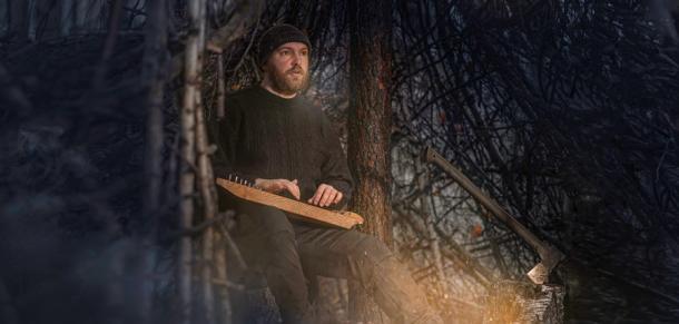 A man playing a kantele in a forest. (Maxim Kukurund /Adobe Stock)