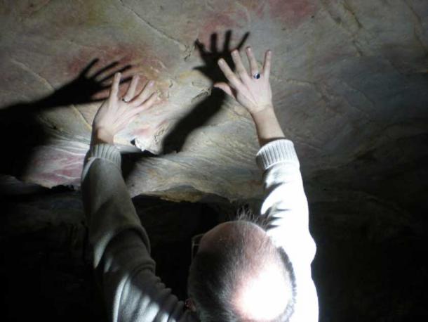 In many cases hand stencils were left on parts of cave walls and ceilings that were difficult to access, such as these in El Castillo cave, with Paul Pettitt showing the position of the hands. Paul Pettitt and cave art dating team. (Author provided/The Conversation)