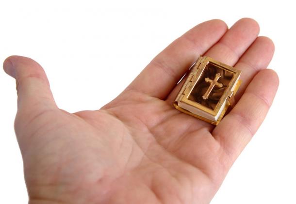 Una Biblia en miniatura en la palma de un hombre. Fuente: Volodymyr/Adobe Stock