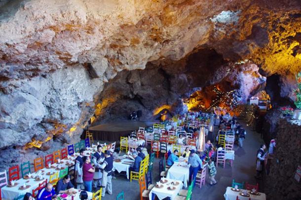 A particularly large cave, also to the East of the Pyramid of the Sun, was converted in modern times into a restaurant and events hall. The people standing and the dining furniture provide a reference for the enormous size of this chamber (Photo by author Marco M. Vigato)