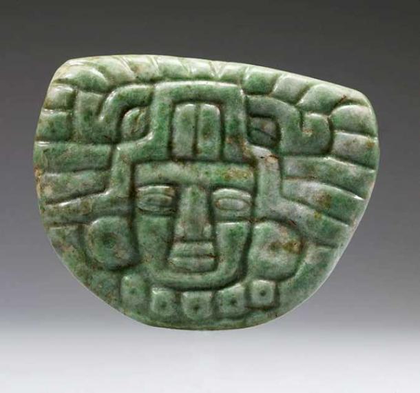 Jade pendant from the Late Classic Maya period. The pendant is carved in the standardized frontal rendering of a noble person wearing the formal head gear of the ruling elite, with unique features that document more than five hundred years of the jadeite carver's art. The flat pendants exemplify Middle and Late Classic figural pendant styles with the distinctive headdresses and impressive jadeite earflares and bead necklaces worn by the nobility. (c. 650 – 850 AD). (Public Domain)