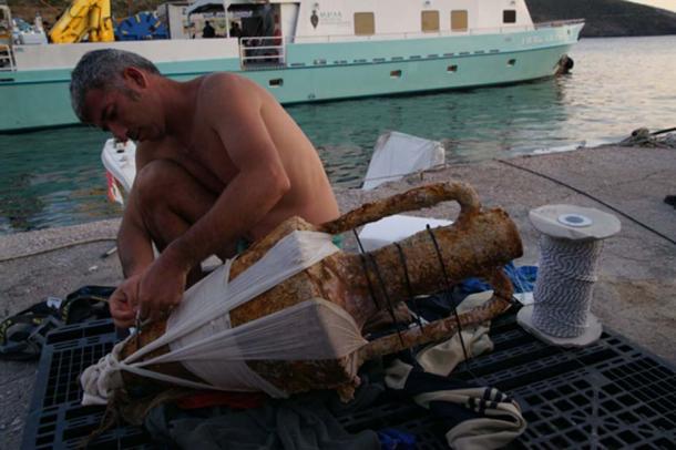 The chief conservator carefully prepares a Classical Period Chian amphora for the conservation tank by Vasilis Mentogianis