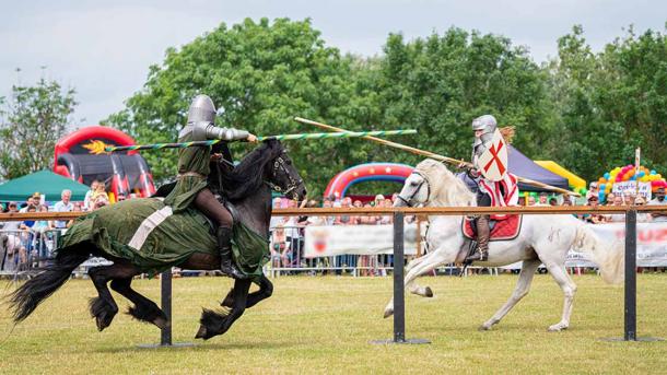 Modern-day reenactment of a jousting tournament, with two knights on jousting horses. (david / Adobe Stock)