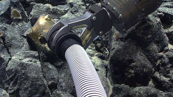 The robotic arm retrieving the weirdly unfamiliar golden orb on Alaska sea floor. (NOAA Ocean Exploration)