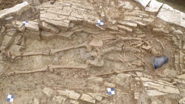 One of the skeletons alongside a pot found at the Roman burial site. (Wessex Archaeology)