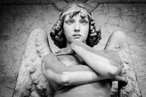 A striking image of a child angel that sits on top of a grave in Staglieno Cemetery (Andrea Vismara / Adobe Stock)