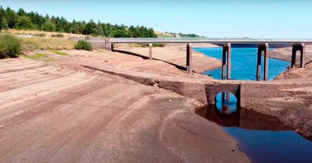 The sunken village of Baitings and its famous packhorse bridge, pictured below the modern car bridge, have been exposed by record drought and heat for the first time since the mid-1950s. (YouTube screenshot / velomoho)