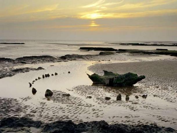 Seahenge during sunset, after some of the timber had been removed by archaeologists for testing and preservation. (Historic England)