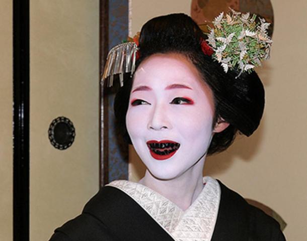 Una mujer con los dientes manchados de negro por la práctica de Ohaguro.