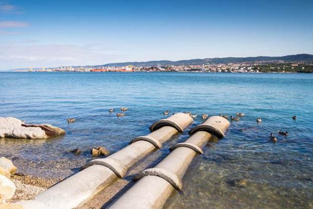 Concrete tubes going into the sea. (eunikas / Adobe Stock)