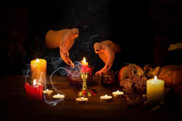 Depiction of witch making passes over candles and wax on an altar in the dark. (junky_jess / Adobe stock)