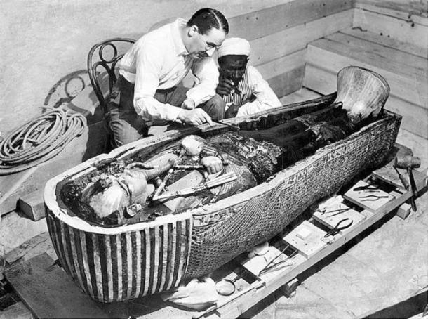 Howard Carter and an Egyptian workman examine the third (innermost) coffin of Tutankhamun made of solid gold, inside the case of the second coffin. (Public Domain)