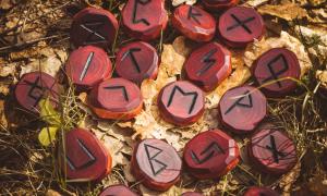 Red runes carved from wood on the ground. There are 24 runes in the Elder Futhark.
