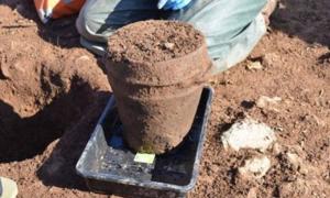 ANU Archaeologist Dr Catherine Frieman & co-director James Lewis with funerary pot in situ.