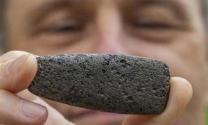 Florida Museum archaeologist Charles Cobb holds an axe head known as a celt. To create this distinct shape, a Chickasaw craftsperson reworked a Spanish iron object to mimic traditional stone versions. Credit: Florida Museum, Photo by Jeff Gage