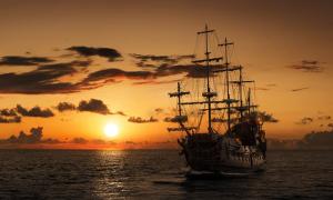 Pirate ship on the open sea at sunset. Representative image of the Queen Anne’s Revenge.