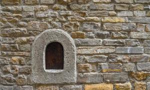 A wine window (buchetta del vino), used in the past to sell wine directly to passers-by, on the old stone wall of an ancient building in the historic centre of Florence, Tuscany, Italy. Source: Simona Sirio /Adobe Stock