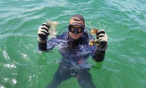 A marine archaeologist holds up intact glass vessels.	Source: Regional Historic Museum Burgas