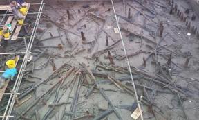 Archaeologists work from scaffolding to excavate a roundhouse that collapsed into the river after a fire. 
