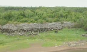 Field archaeologist Michael Gibbons, left, discovered the outlines of this gigantic Bronze Age fortress, partially visible in the background of this image, which may be nearly 3,200 years old, while carrying out routine field work in a nature preserve in County Galway, Ireland.	Source: YouTube screenshot / RTE News