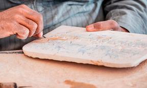 An artisan carves Egyptian hieroglyphs on a stone tablet. Source: EdNurg / Adobe Stock.