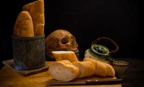 Grinding bones into bread - human skull and fresh bread.