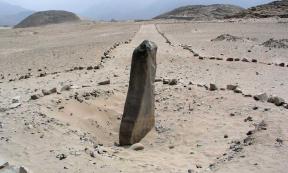 The monolith called Huanca with pyramids in the background in Caral-Supe 