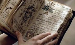 Person holding an ancient grimoire filled with spells, curses, and incantations