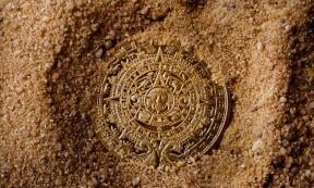 Aztec coin in sand. Source: breakermaximus / Adobe Stock.