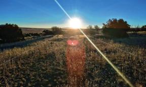 View of the northern parallel Gasco Road on the morning of the winter solstice in 2022, with Mount Taylor directly beneath the sun in the distance.
