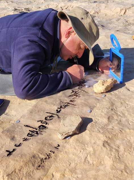 An archaeologist traces one of the inscriptions found on a rock. (Roman Garba and Alžběta Danielisov/ Institute of Archaeology of the CAS in Prague)